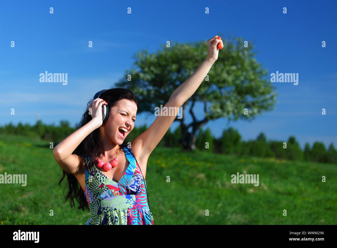 Giovane donna con le cuffie per ascoltare musica sul campo Foto Stock