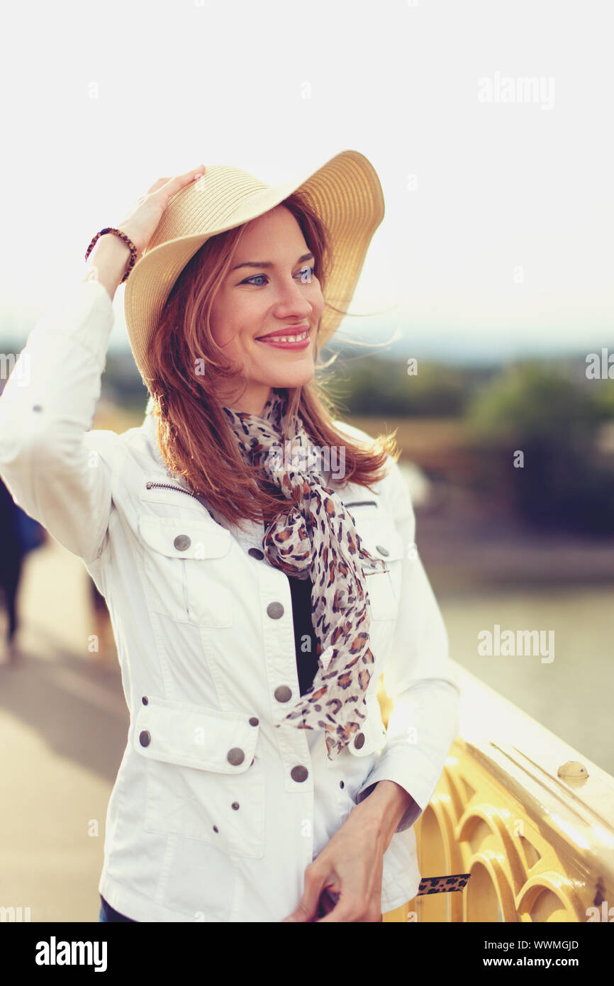 Felice giovane donna in hat guardando lontano sul ponte di autunno Foto Stock