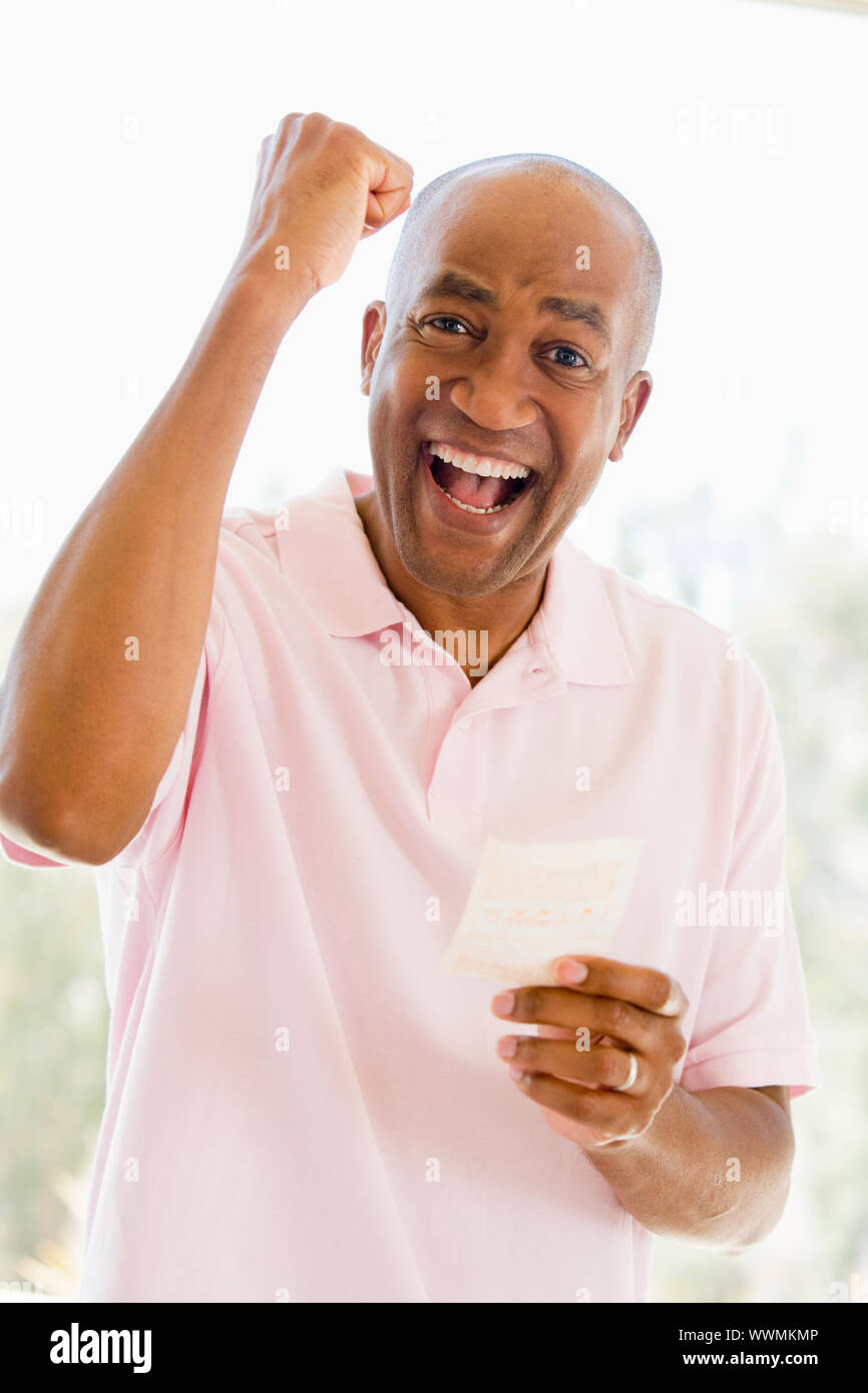 L'uomo con la vincita del biglietto della lotteria eccitato e sorridente Foto Stock