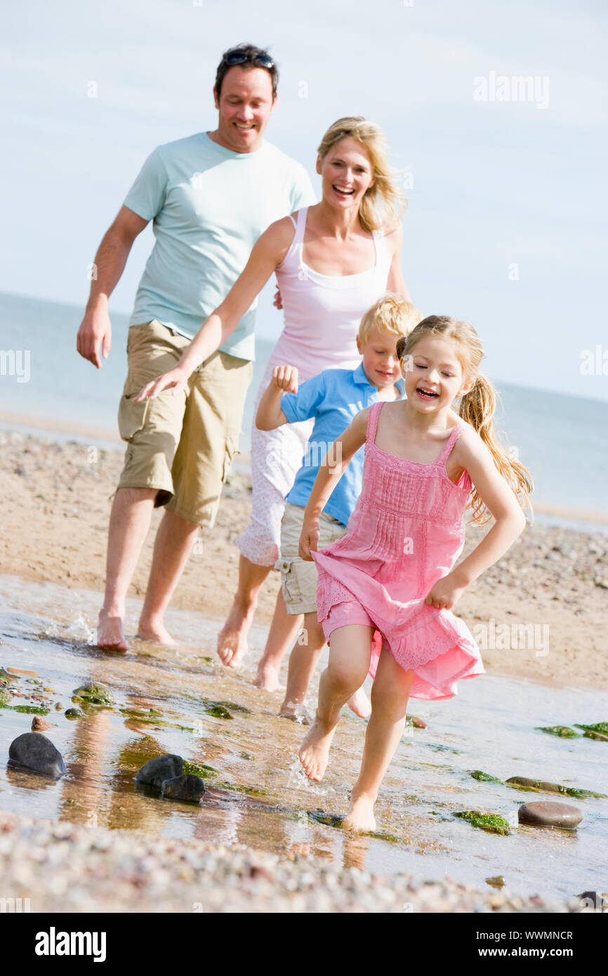 Famiglia in esecuzione presso la spiaggia di sorridere Foto Stock