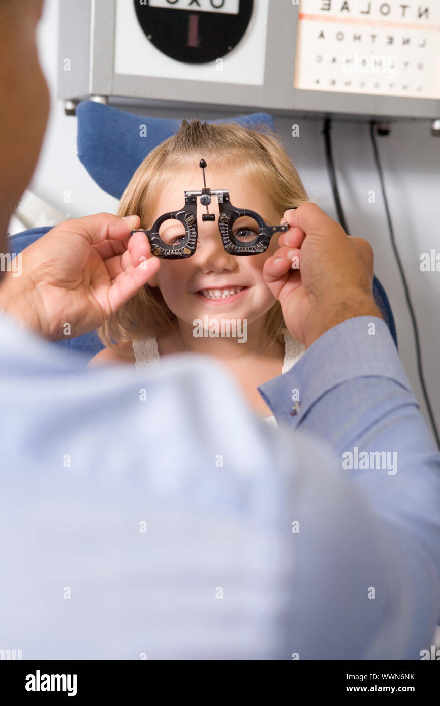 All'ottico optometrista in sala esame con ragazza in sedia a sorridere Foto Stock