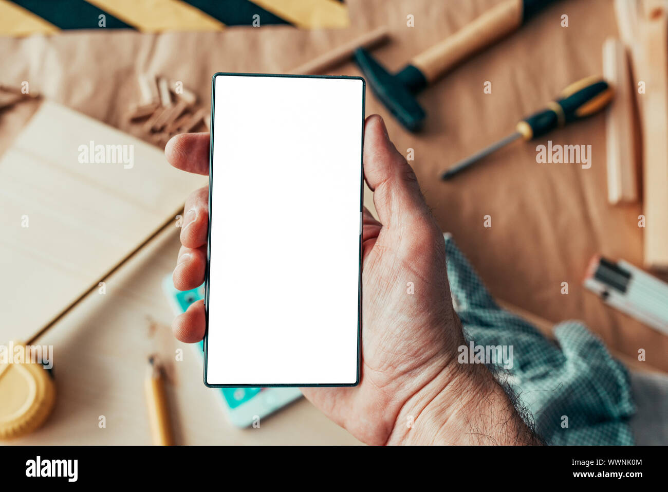 Tuttofare manutentore azienda smartphone con vuoto mock up schermo al di sopra del banco di officina con strumenti Foto Stock