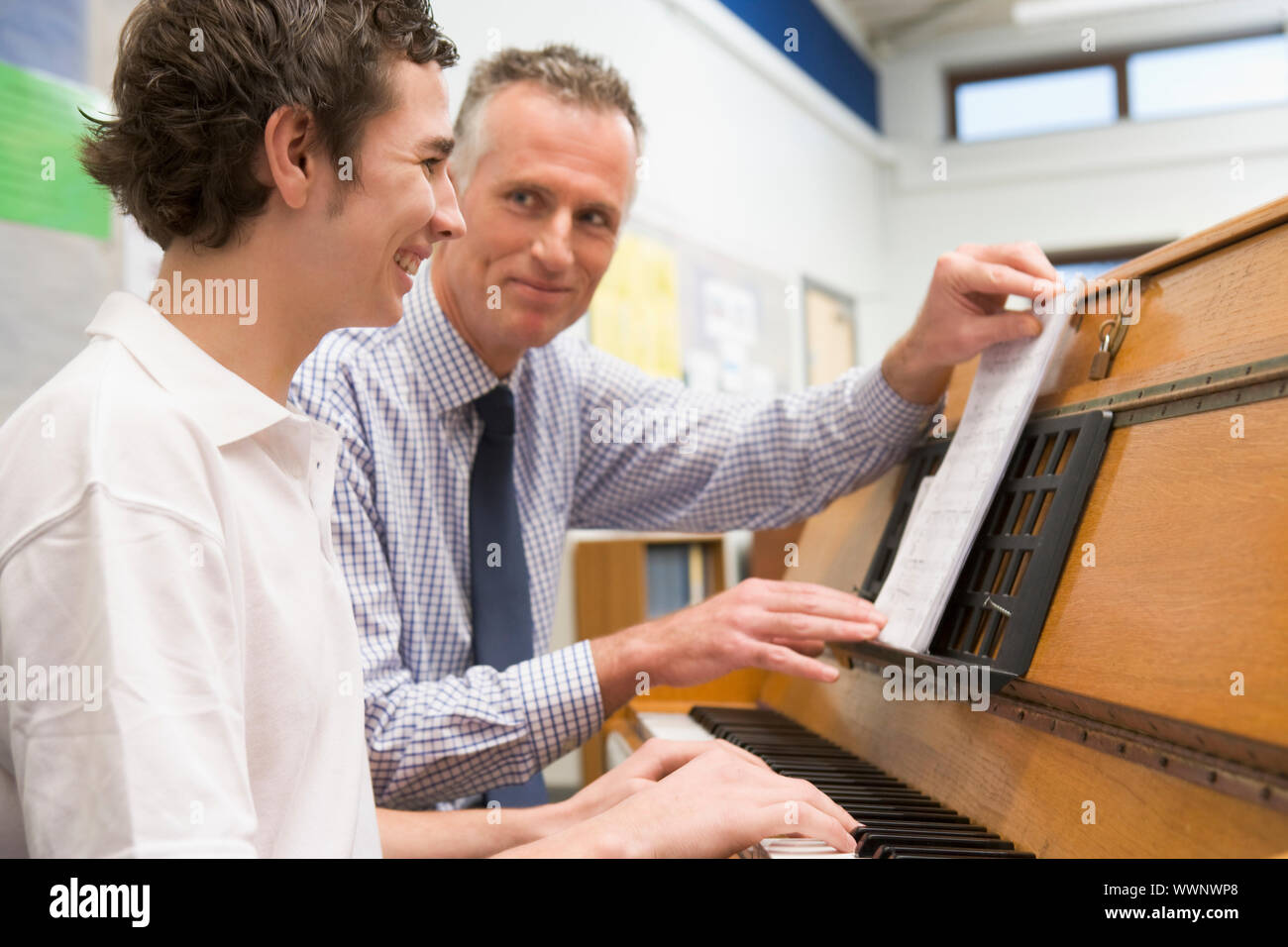 Maschio di apprendimento dello studente pianoforte con insegnante in classe Foto Stock