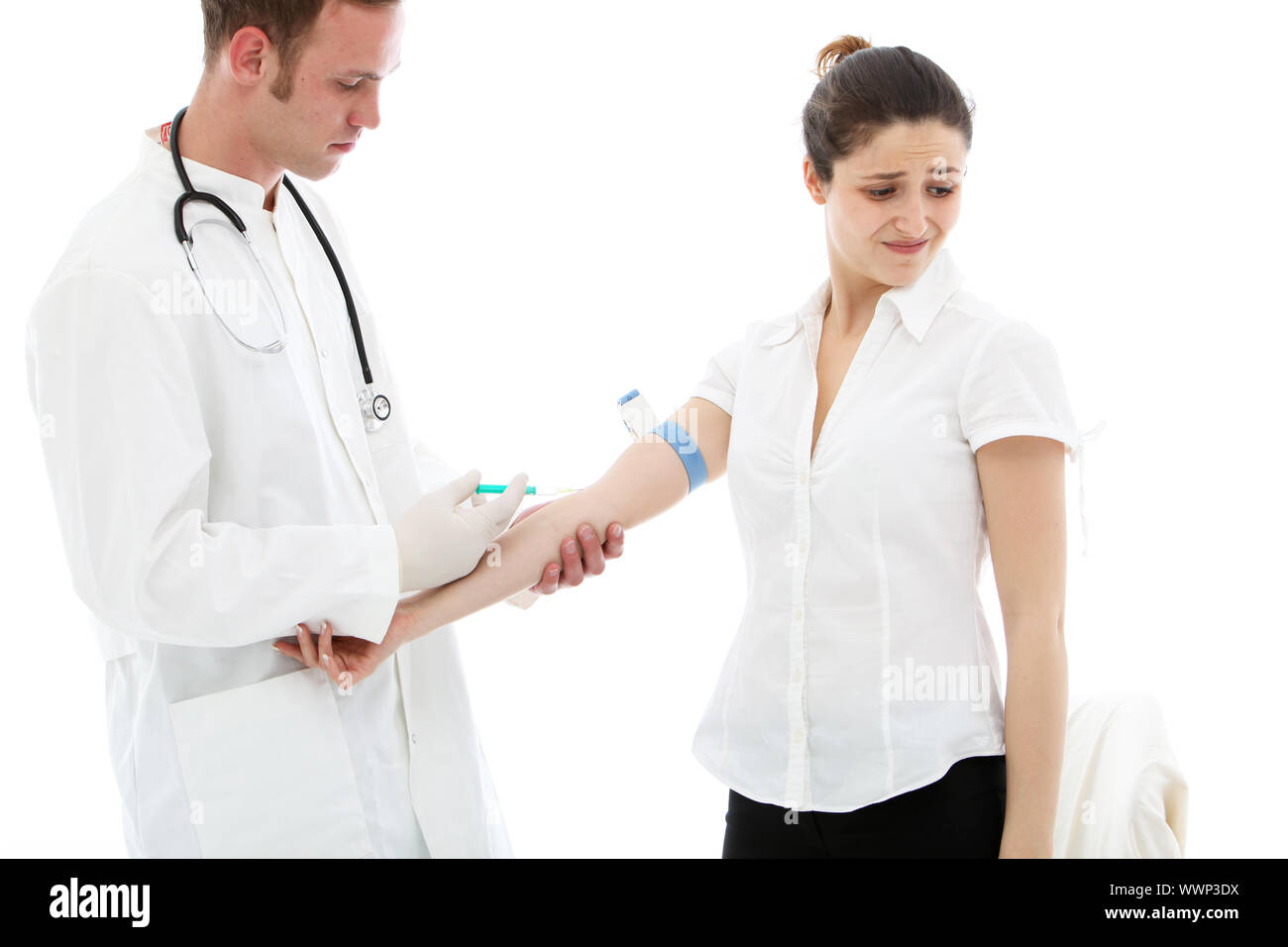 Un giovane maschio medico, studente o l'infermiera di somministrare una iniezione endovenosa di un paziente di sesso femminile che è alla ricerca di distanza con una grimace Foto Stock