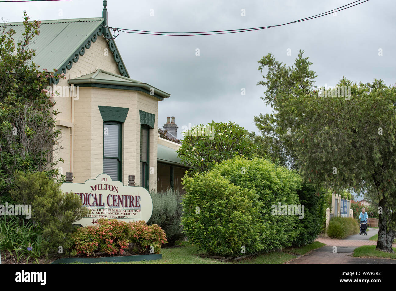 Un piccolo centro medico nella cittadina rurale di Milton nel Nuovo Galles del Sud, Australia con una donna più anziana a piedi lungo un sentiero verso di esso Foto Stock