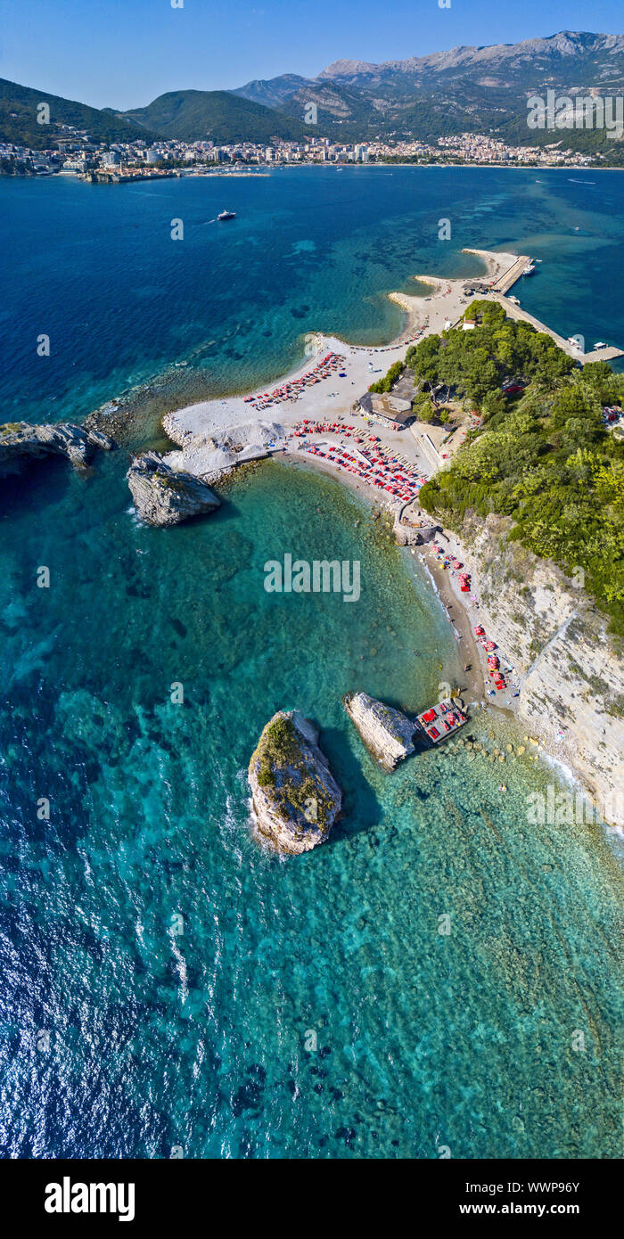 Vista aerea di Sveti Nikola, isola di Budva, Montenegro. Hawaii spiaggia, ombrelloni e bagnanti e acque cristalline. Coste frastagliate Foto Stock