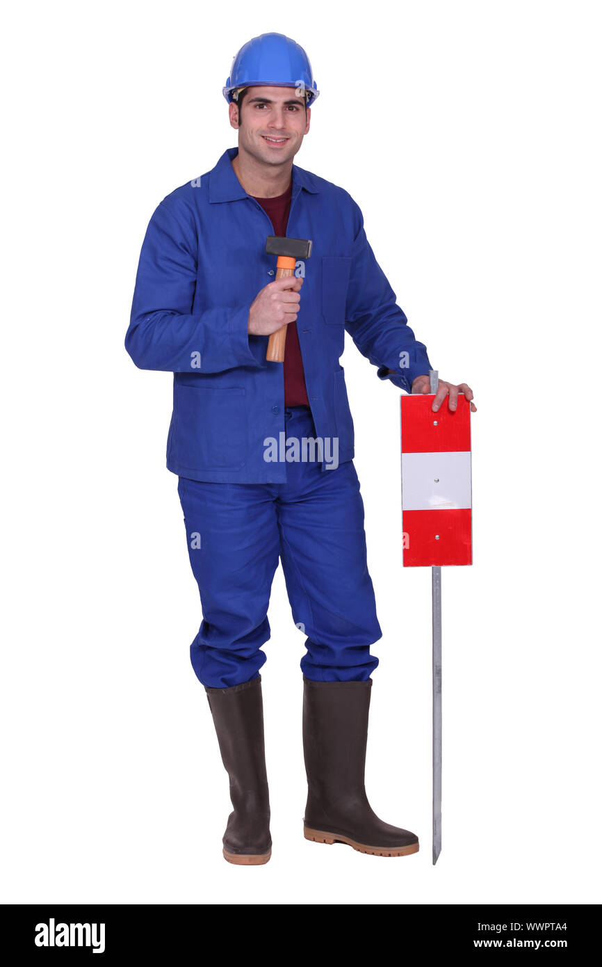 Operaio edile in piedi con un mazzuolo e segno di traffico Foto Stock