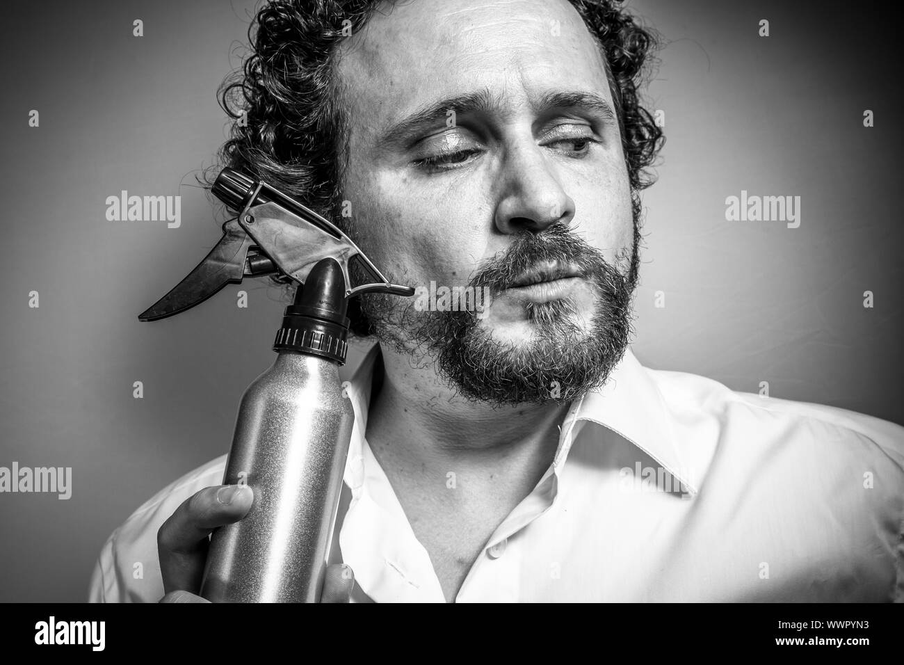 Lo spray per la pulizia, l'uomo con intensa espressione, camicia bianca Foto Stock