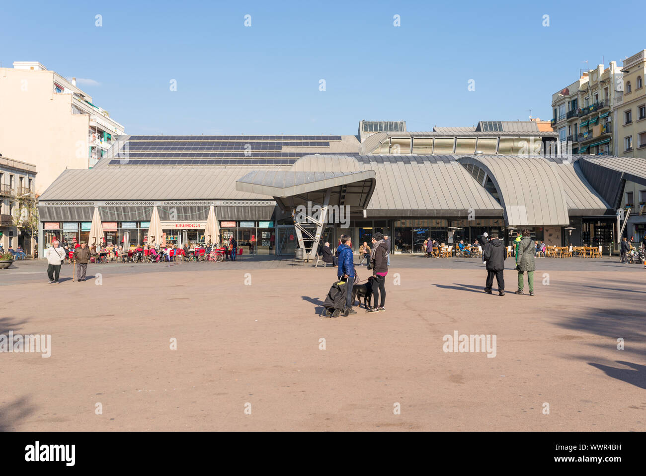 Turisti e abitanti godetevi il sole di giorno al di fuori del mercato pubblico Mercat de la Barceloneta Foto Stock
