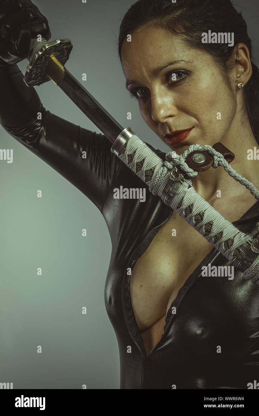 Brunette donna vestita di nero latex, Katana giapponese Foto Stock