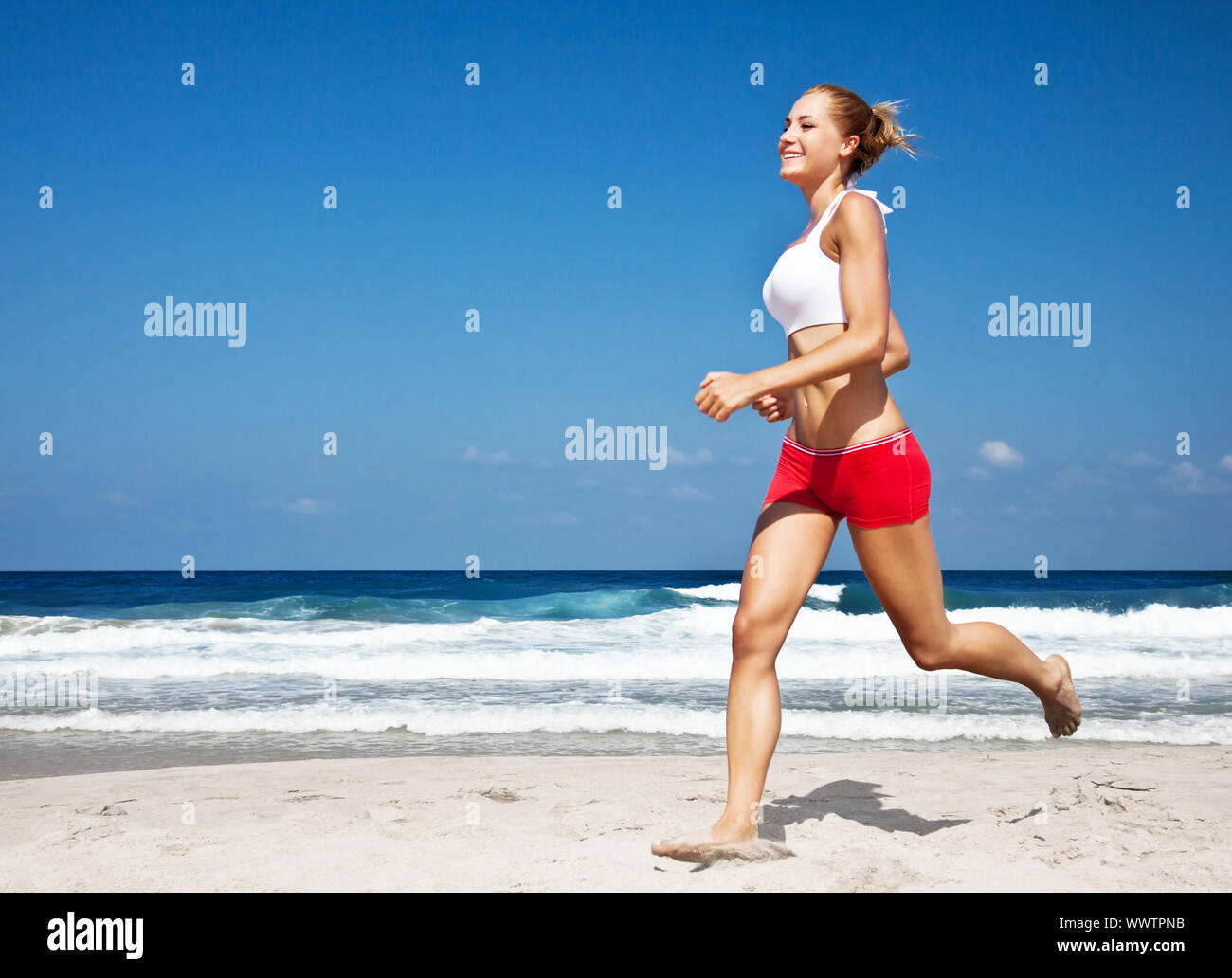 Donna sana in esecuzione sulla spiaggia Foto Stock