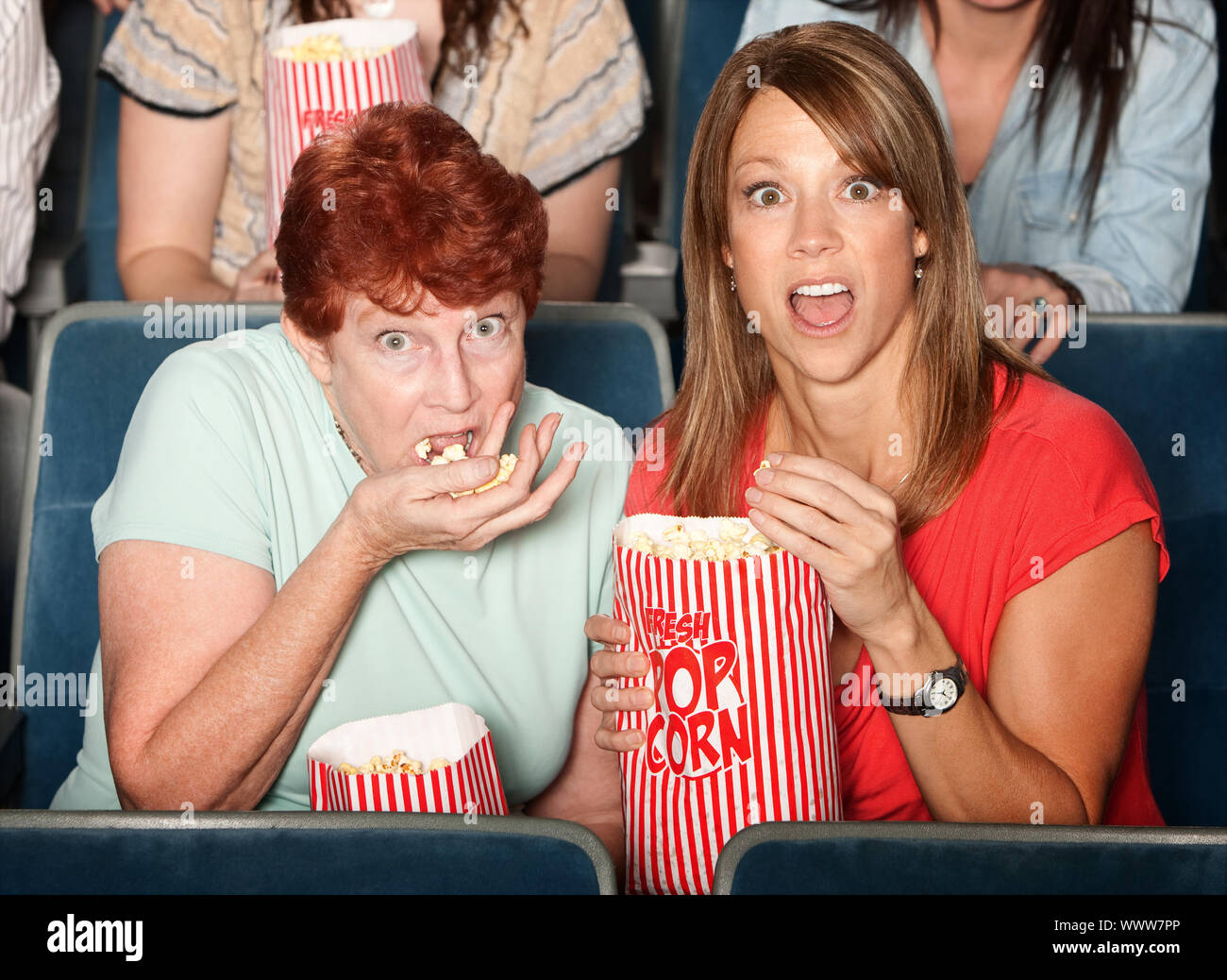 Spaventata Caucasian ladies in teatro mangiare popcorn Foto Stock