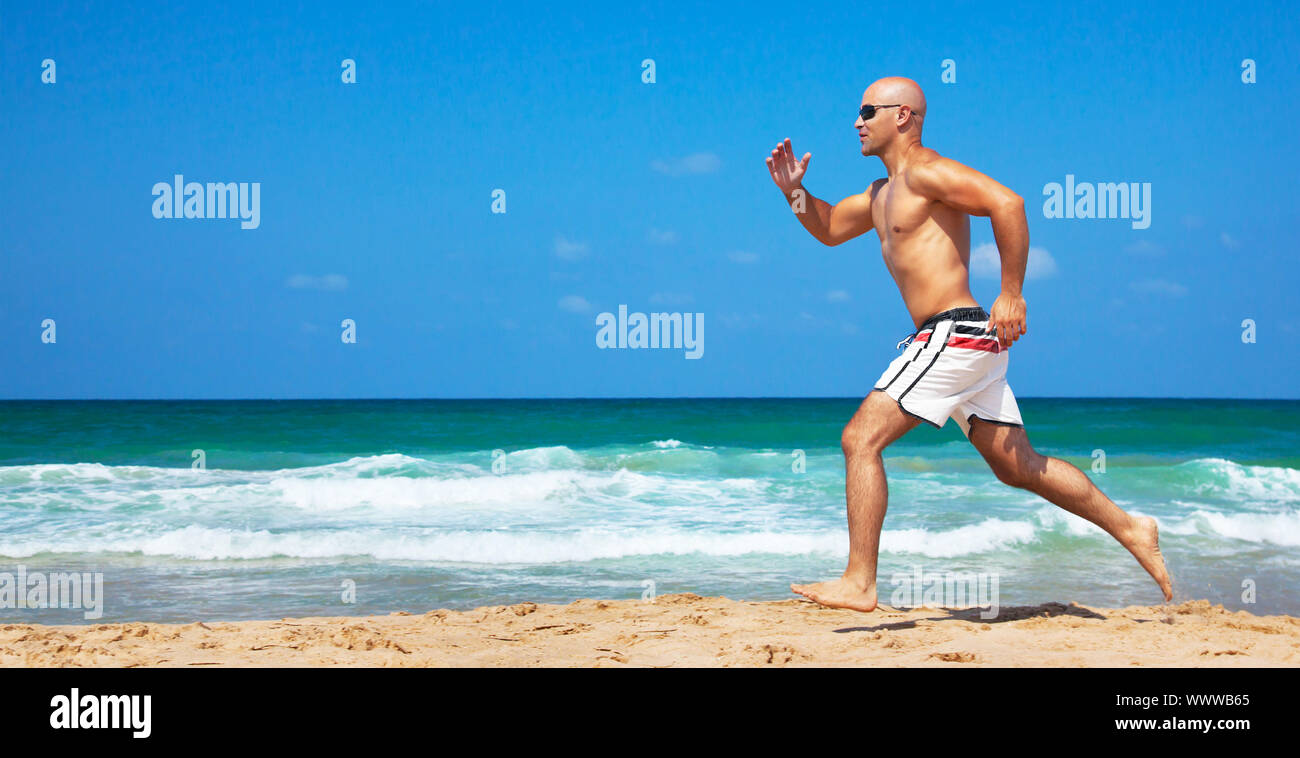 Un sano uomo correre sulla spiaggia Foto Stock