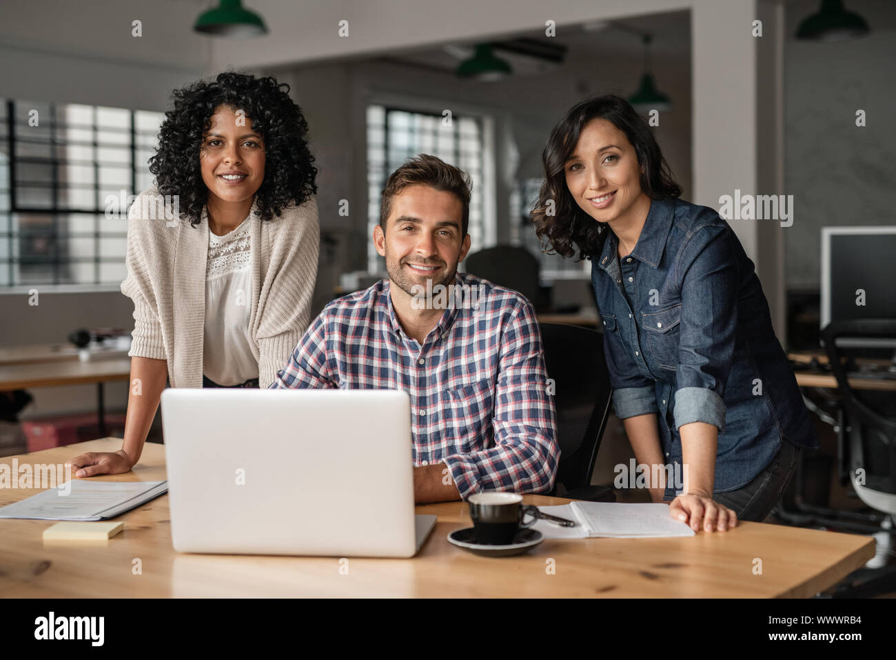 Sorridente giovani designer che lavorano insieme a una scrivania in ufficio Foto Stock