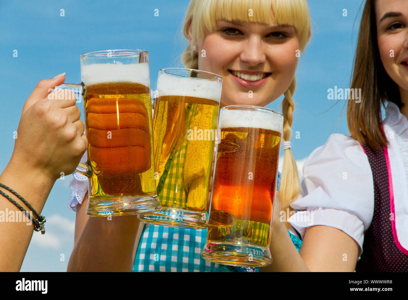Ragazza in un tradizionale Dirndl bere birra nella natura Foto Stock