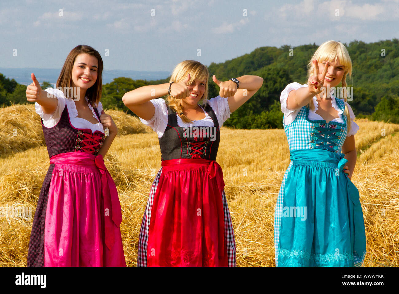 Le tre ragazze vestito con grembiule colorato con il pollice in alto Foto Stock