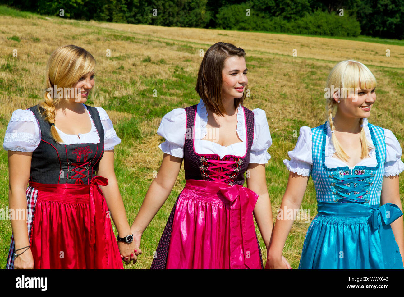 Tre felice e allegro le ragazze in colorate dirndl Foto Stock