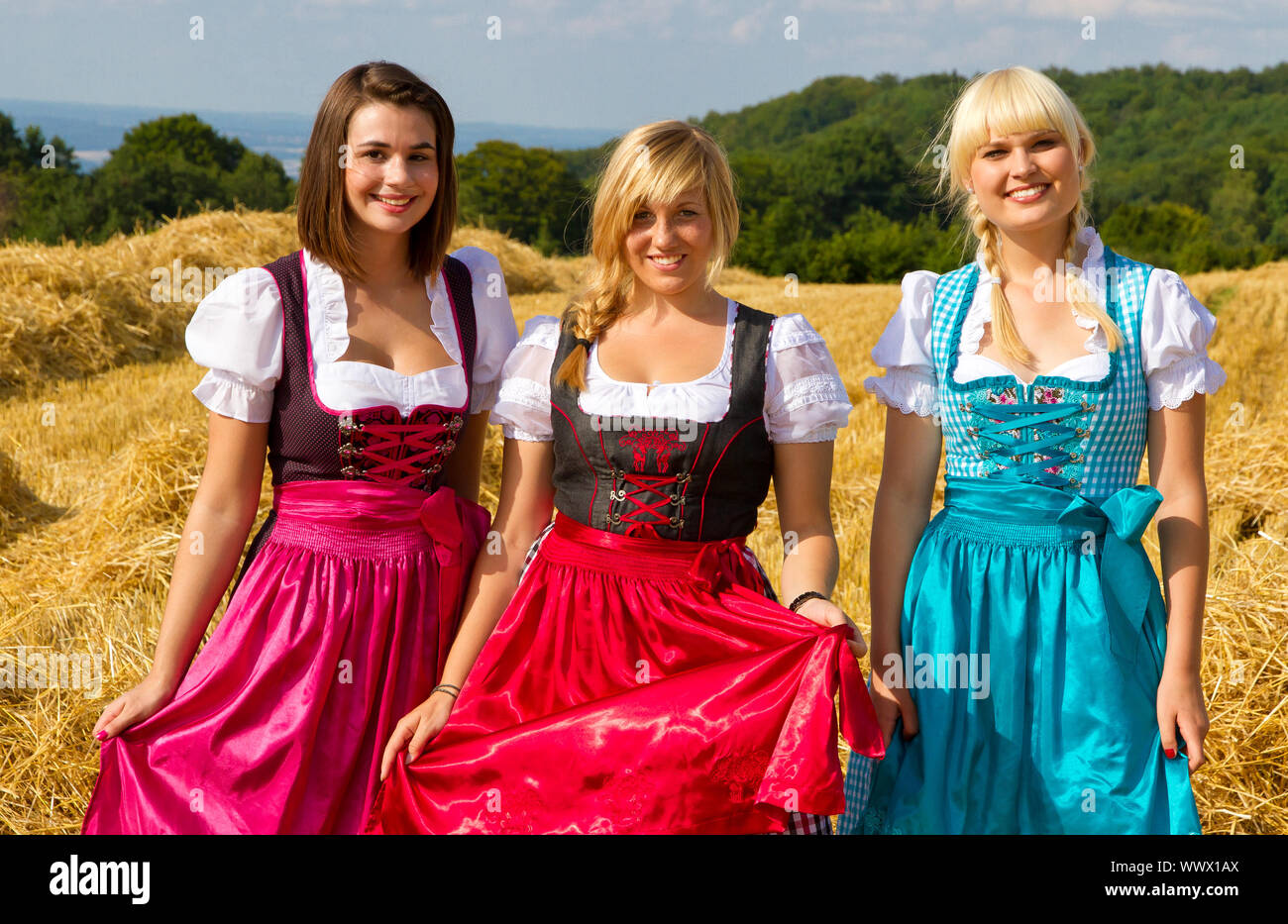 Ritratto di tre beautiufl ragazze vestite con colori vivaci e tradizionali dirndl Foto Stock