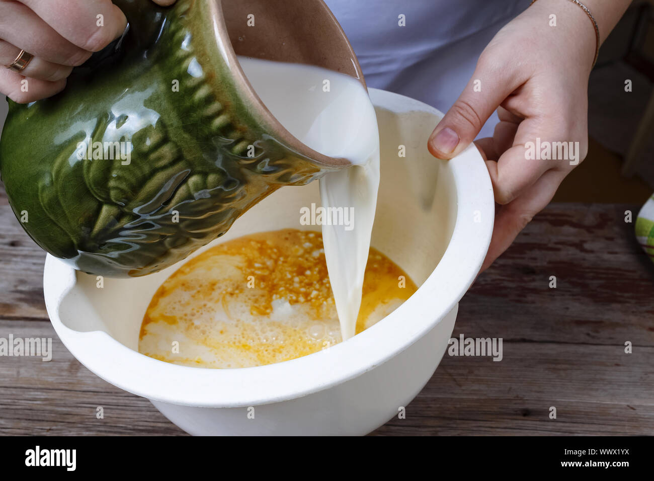La cottura di alimenti. Donna cook versa il latte in una ciotola. Prodotti da forno. Foto Stock