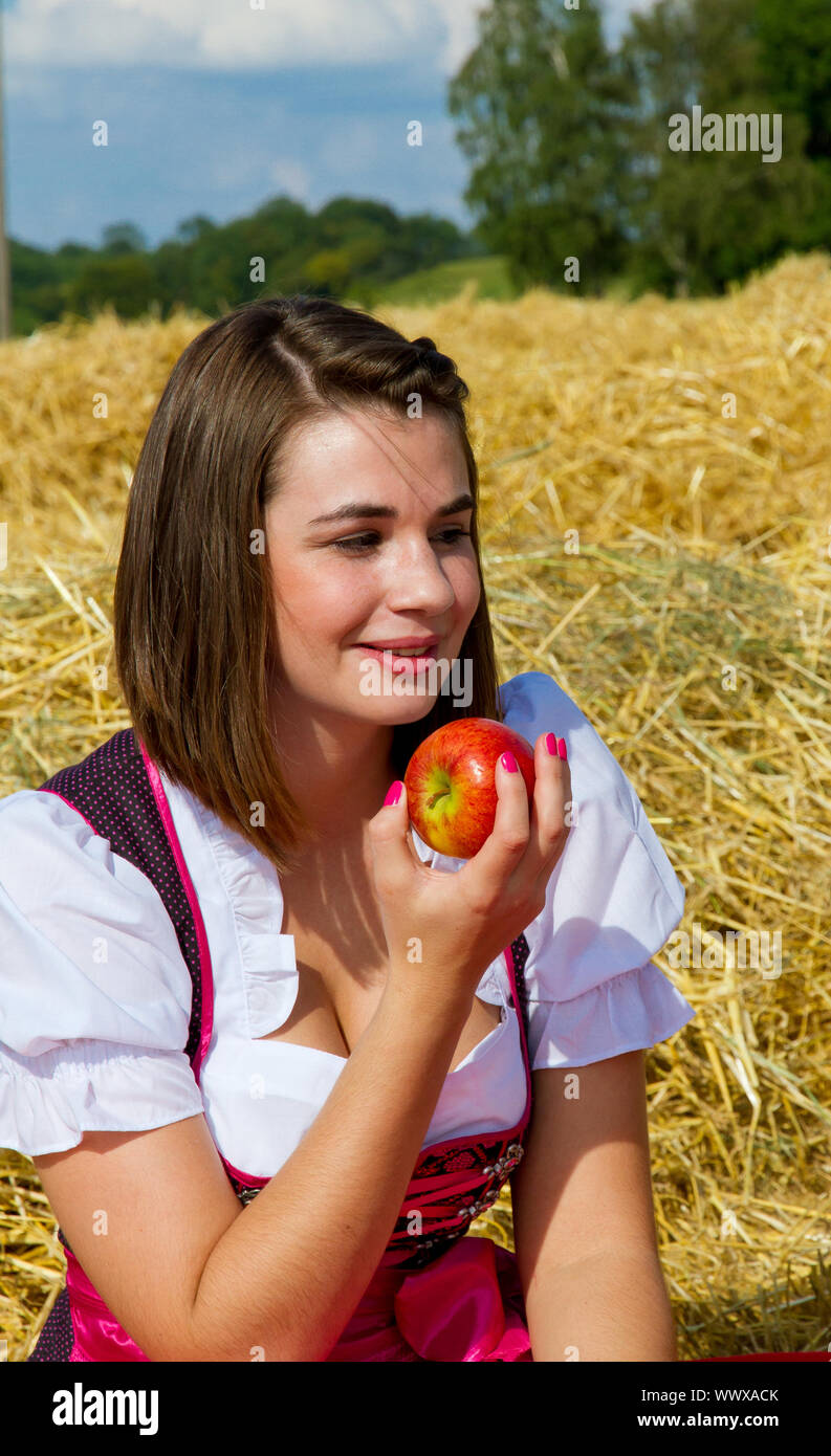 Giovane donna vestita di un grembiule di mangiare un Apple Foto Stock