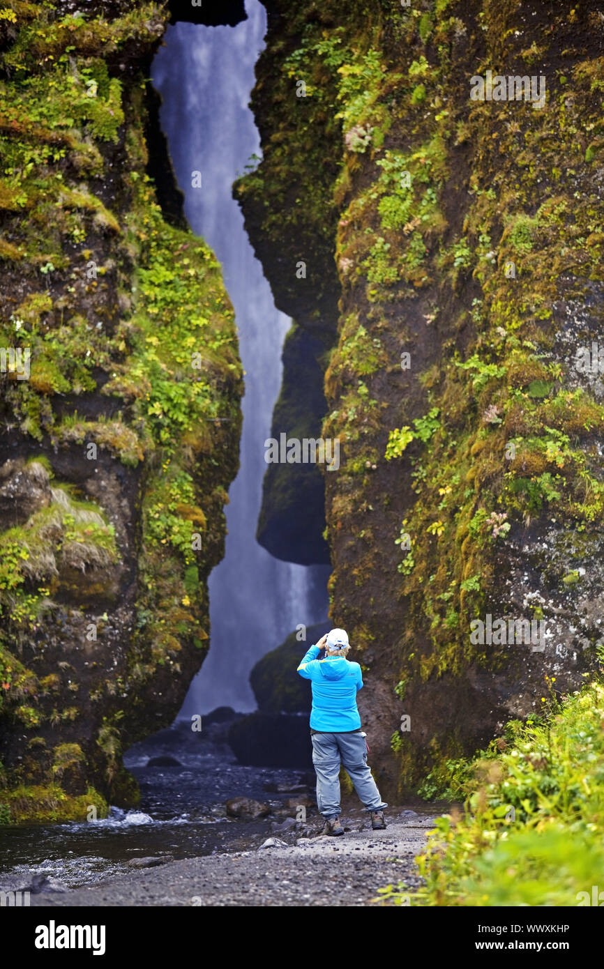 Turistica prendendo foto della piccola cascata Glufrafoss, Seljaland, Sud Islanda, Islanda, Europa Foto Stock