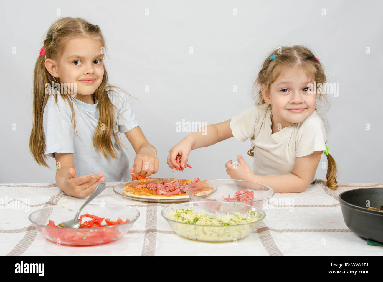 Due poco felice ragazza al tavolo sparso sulla pizza ingredienti Foto Stock