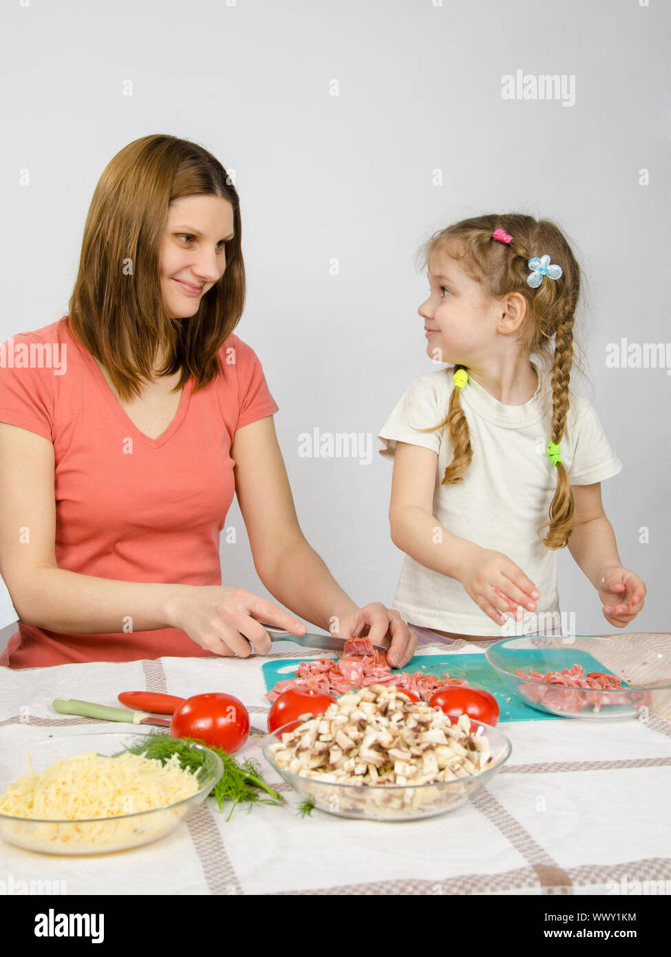 Poco oltre sei anni vecchia ragazza gioioso entusiasmo aiuta la mamma a preparare il cibo Foto Stock