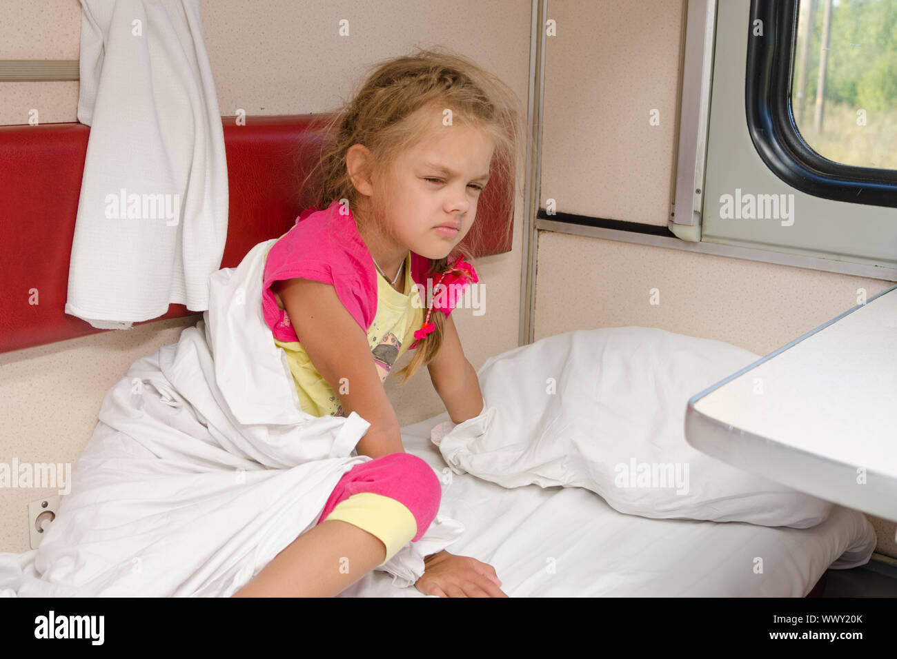 La ragazza sul treno sleepily ottiene dal letto sulla parte inferiore posto in seconda classe carro abitacolo Foto Stock