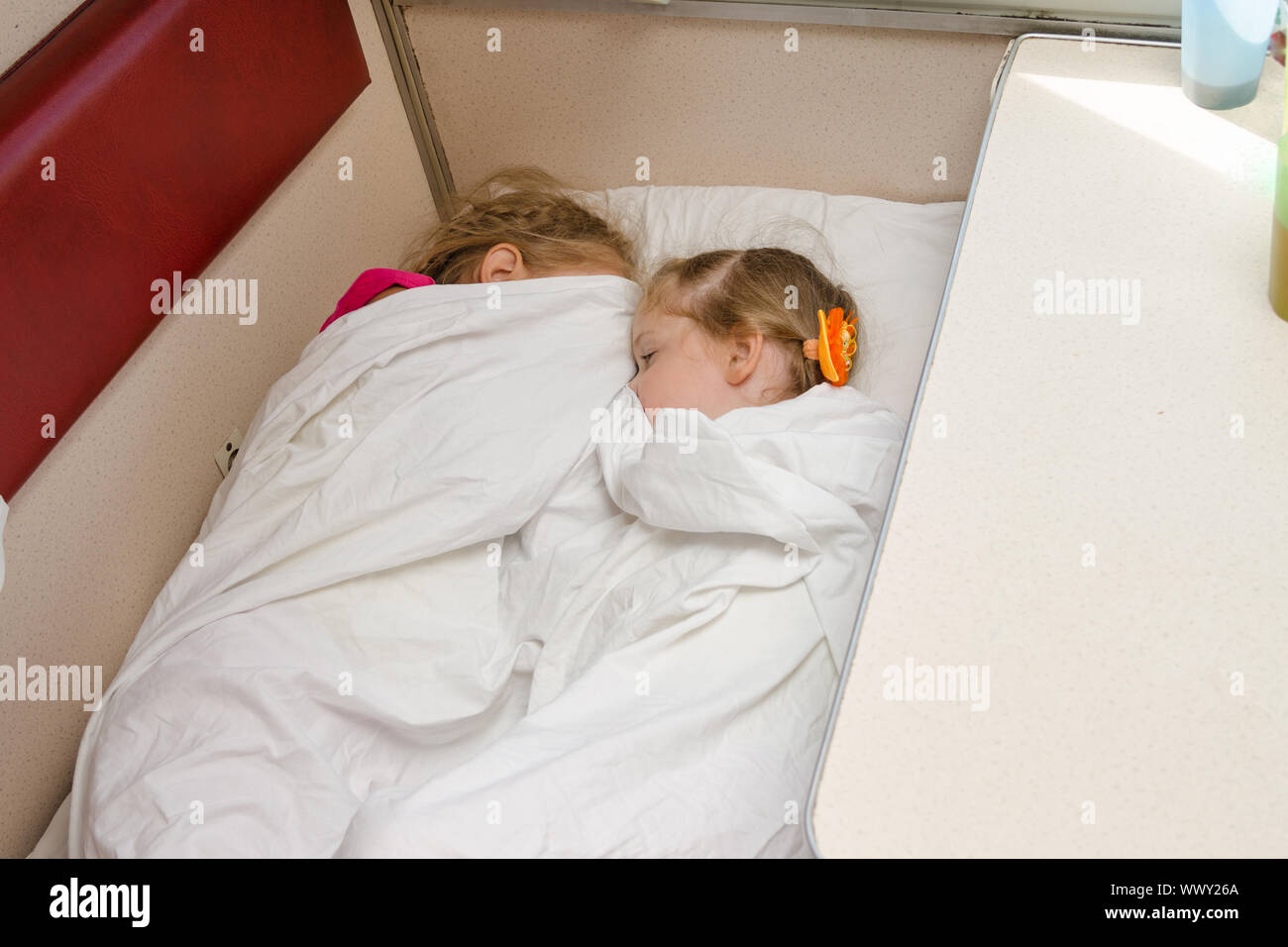 Due bambini dormono sul treno sullo stesso punto di massa nella seconda classe carro abitacolo Foto Stock