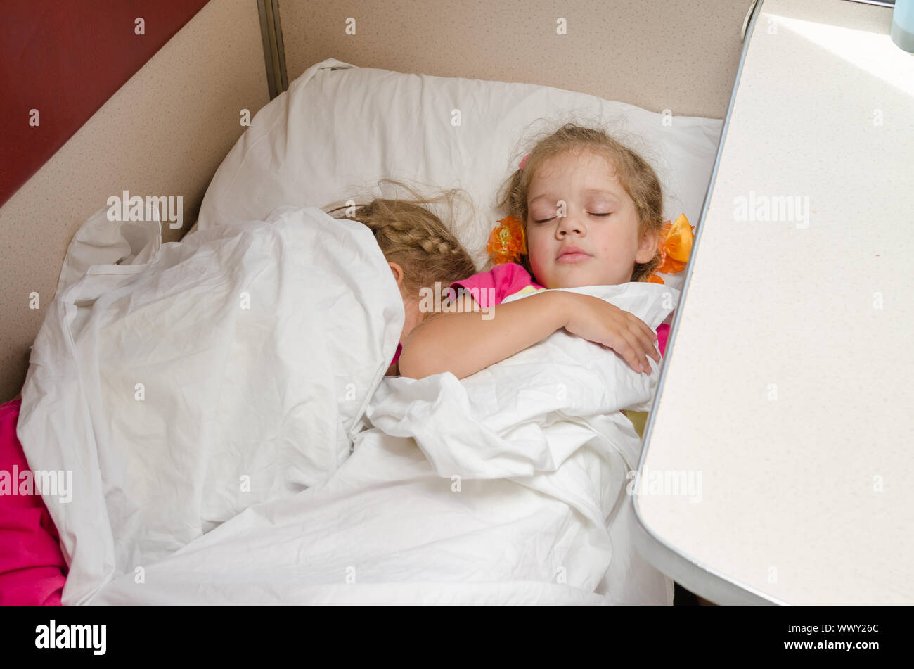 Due bambini dormono sul treno sullo stesso punto di massa nella seconda classe carro abitacolo Foto Stock