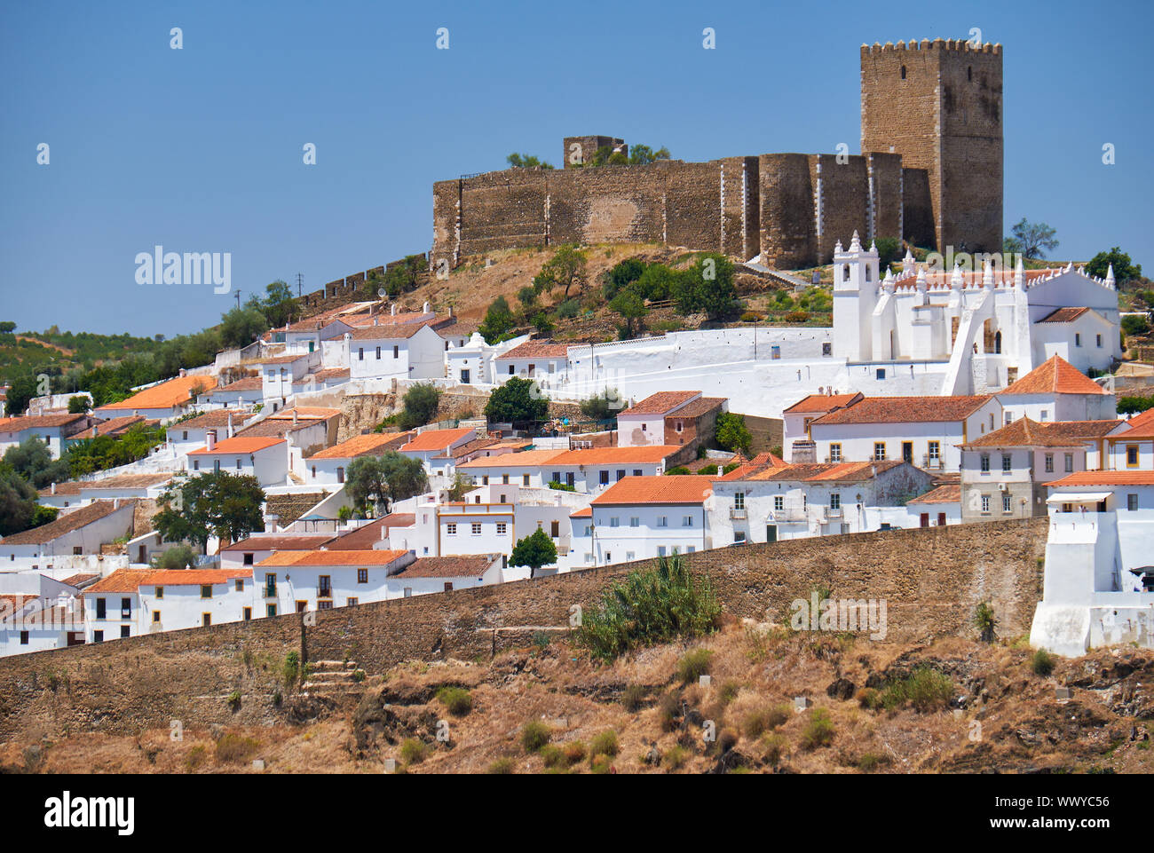 Il castello medievale sulla cima di una collina e circondato da case residenziali di Mertola. Portogallo Foto Stock