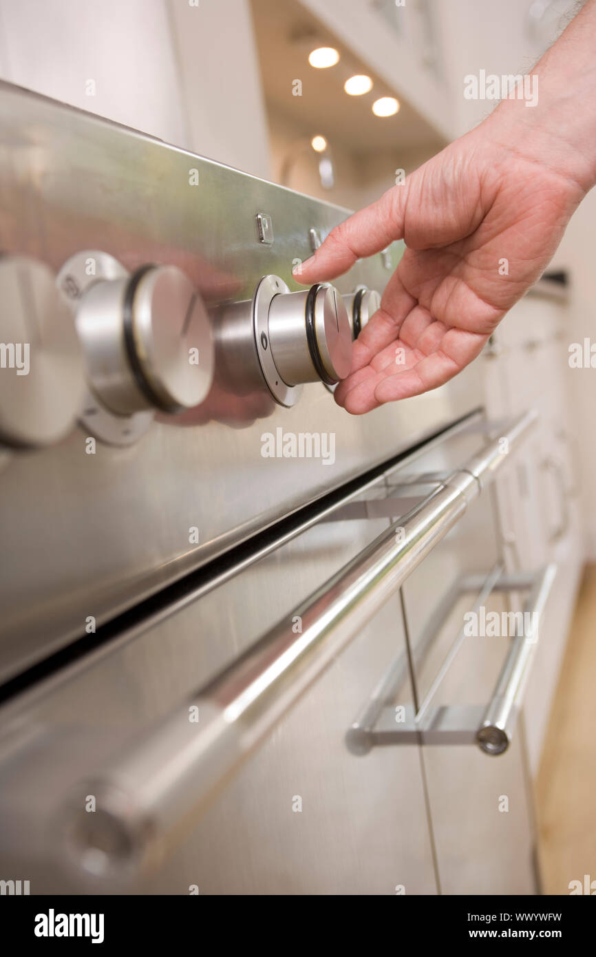 Mano sul quadrante di stufa in cucina Foto Stock