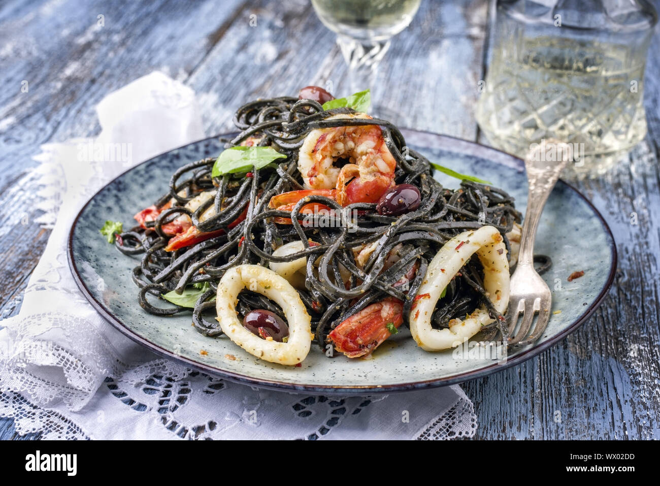 Italian linguine con tinta de i calamari e scampetti con olive come close-up su una piastra Foto Stock