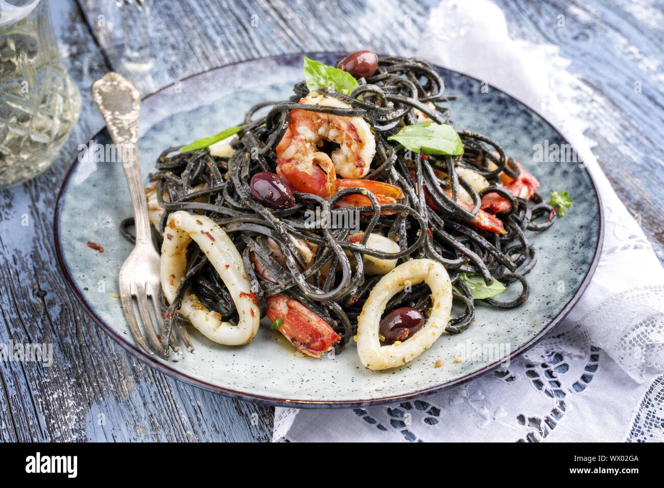 Italian linguine con tinta de i calamari e scampetti con olive come close-up su una piastra Foto Stock