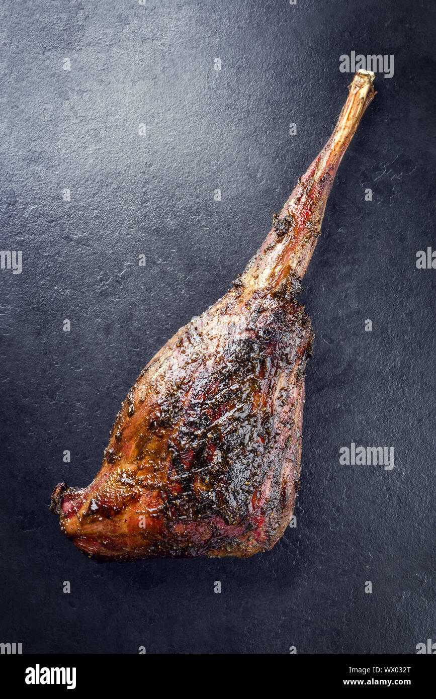 Haunch barbecue di carne di cervo con la marinata come close-up su una lastra di ardesia Foto Stock
