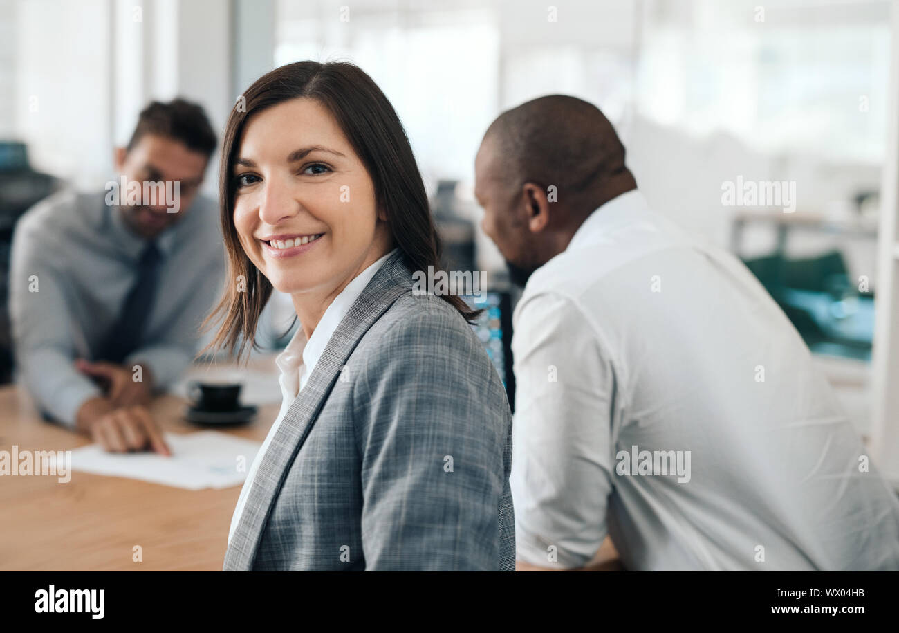 Imprenditrice sorridente seduto in un ufficio sale riunioni con i colleghi Foto Stock