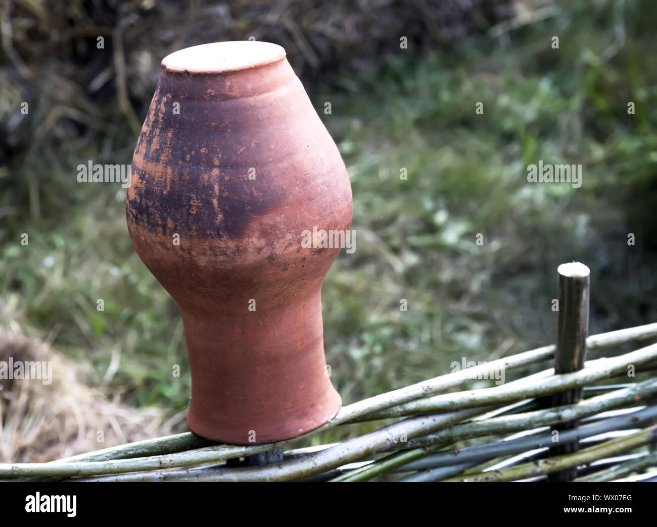 Un antico brocca di argilla in un recinto di vimini. Foto Stock