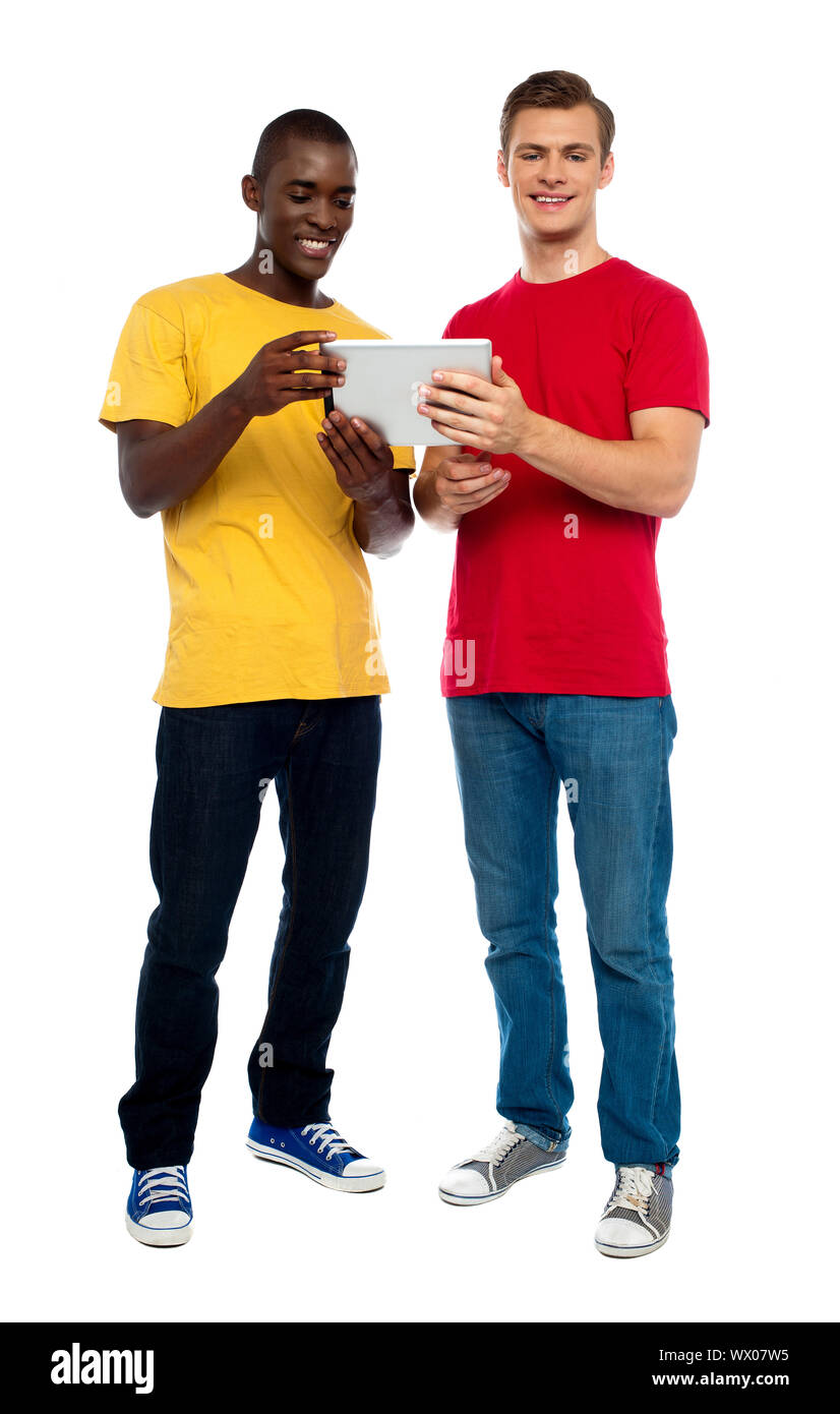 A piena lunghezza shot di ragazzi di funzionamento dispositivo portatile contro uno sfondo bianco Foto Stock