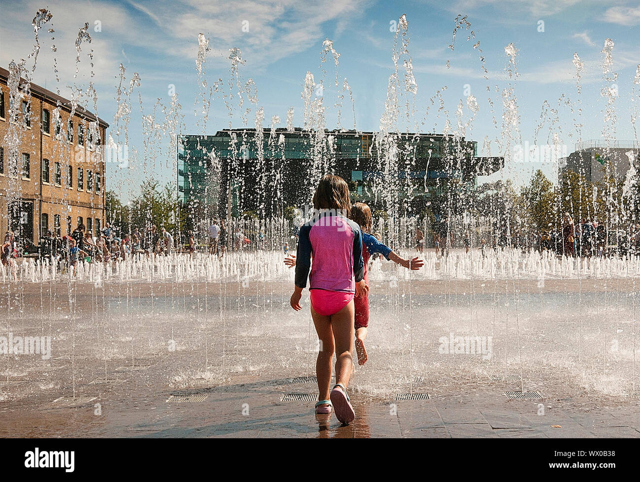 Bambini a giocare con le fontane in Granery Sq Kings Cross London REGNO UNITO Foto Stock