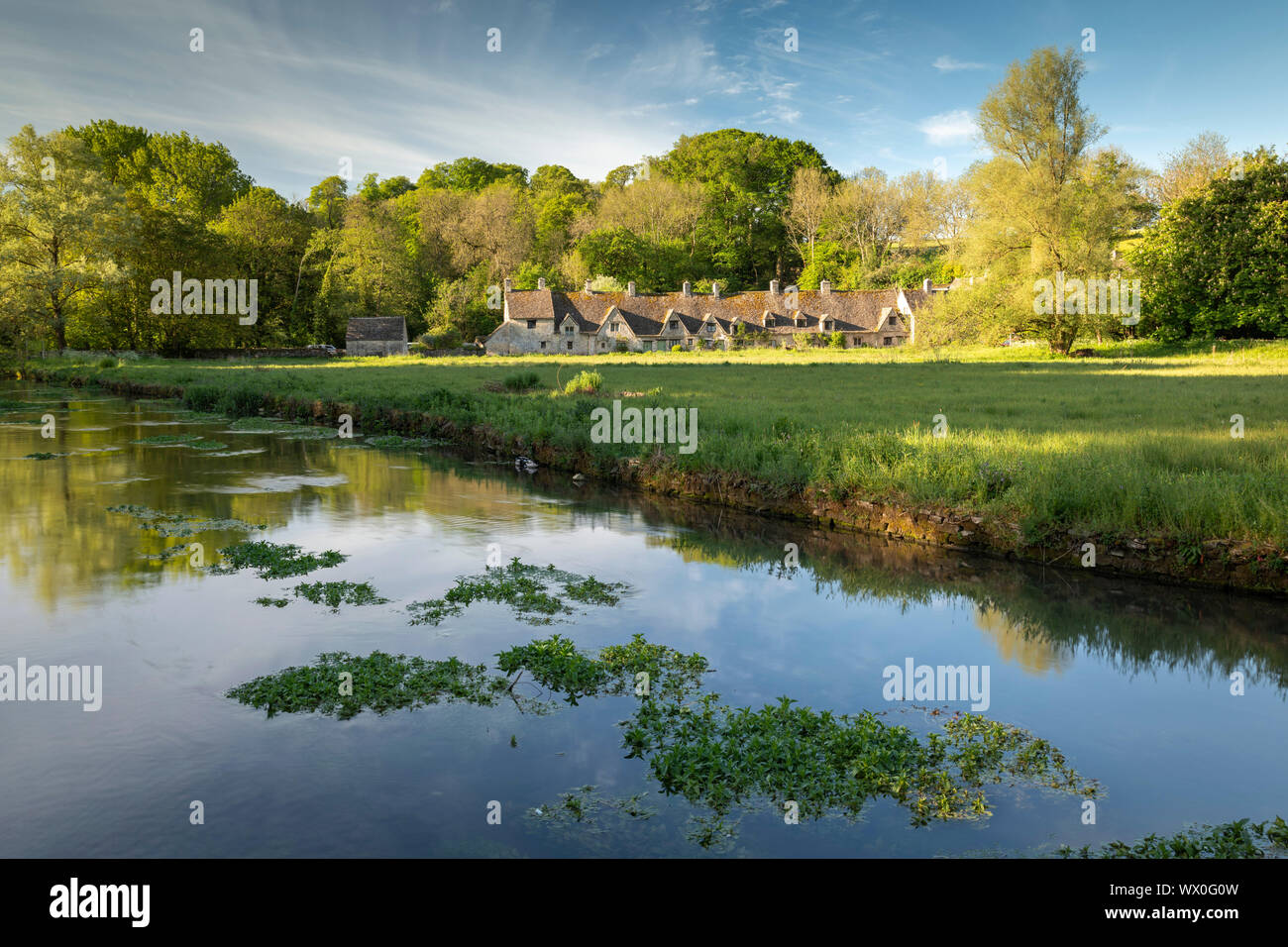 Arlington Row cottages attraverso il Fiume Coln in Cotswolds village di Bibury, Gloucestershire, England, Regno Unito, Europa Foto Stock