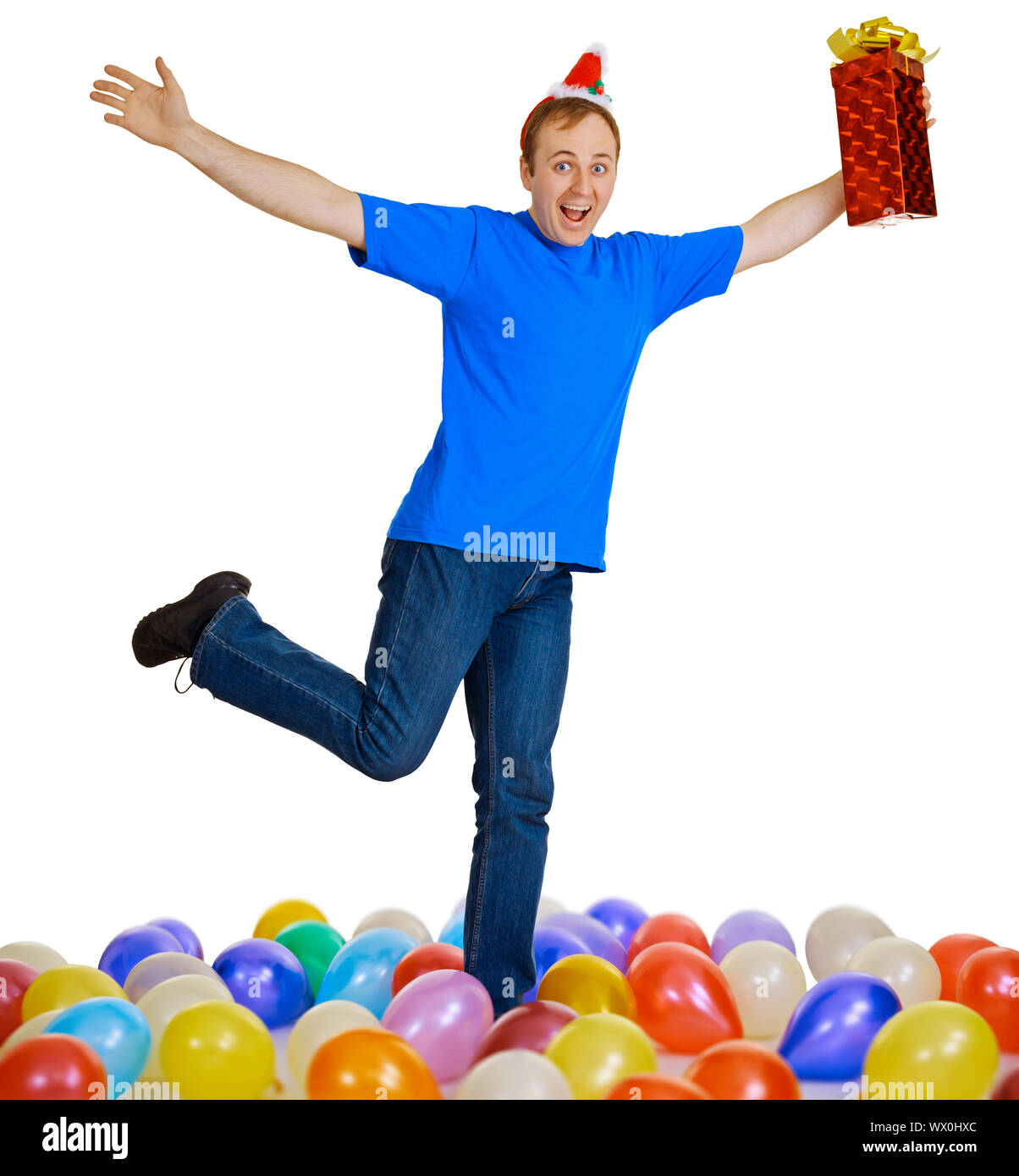 Un uomo felice con un regalo di Natale ballando tra sfere Foto Stock