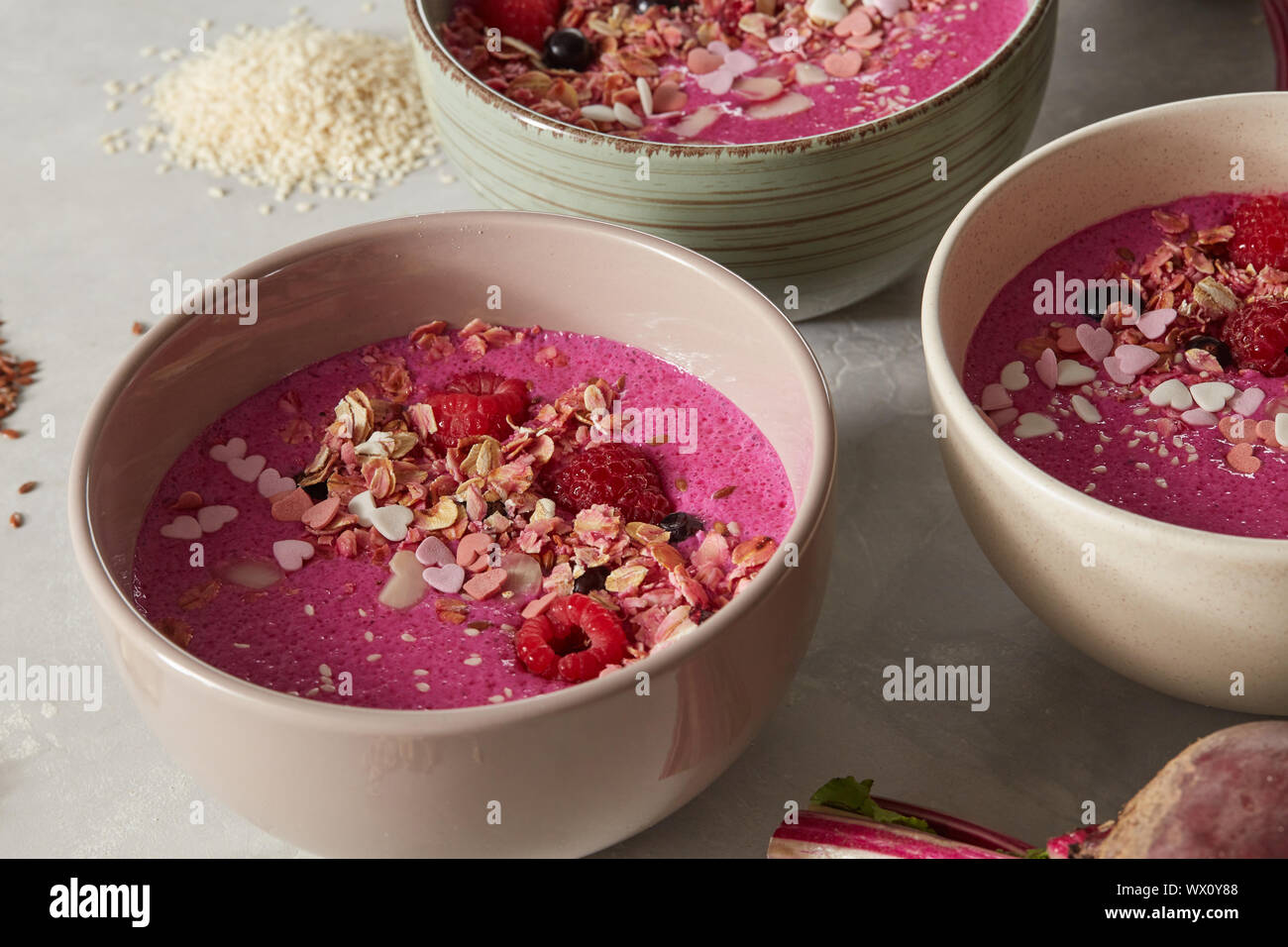 Una sana colazione frullato rosso bocce guarnita con frutta e bacche Foto Stock
