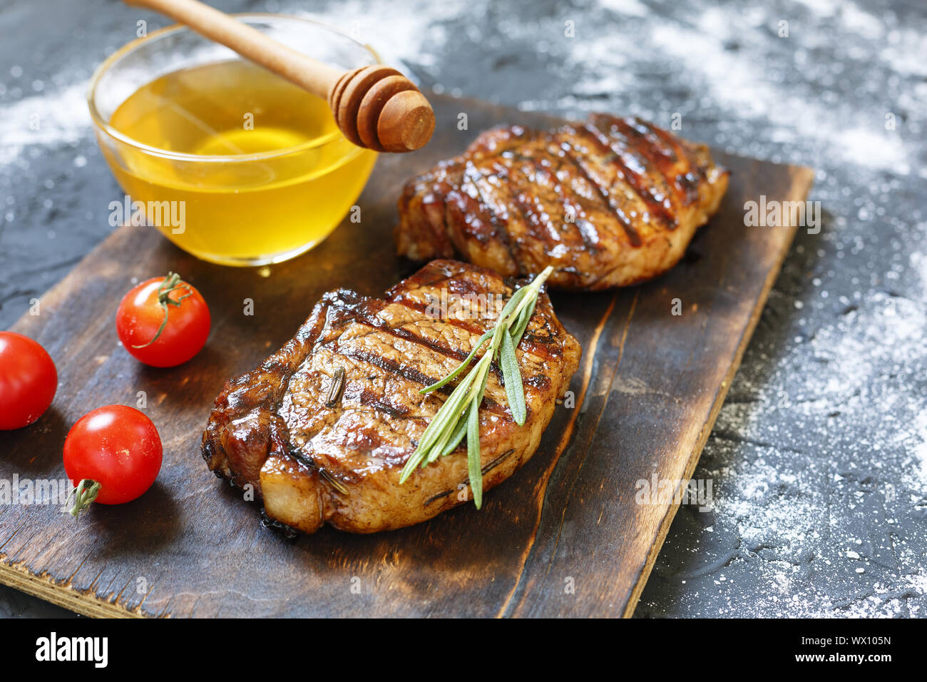 Barbeque, bistecche alla griglia, rosmarino, miele, tagliere di legno, cena preparazione, closeup. copia sp Foto Stock