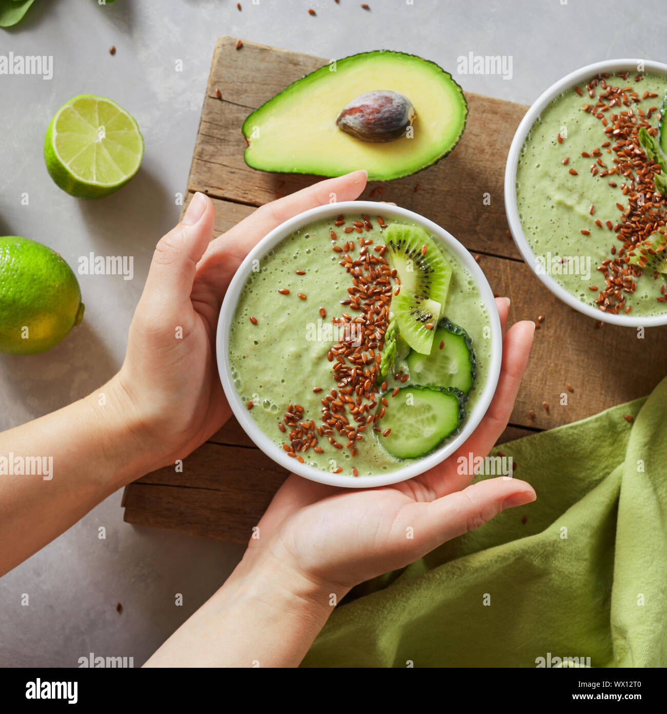 In mani femminili di una ciotola con verde Frullati salutari Foto Stock