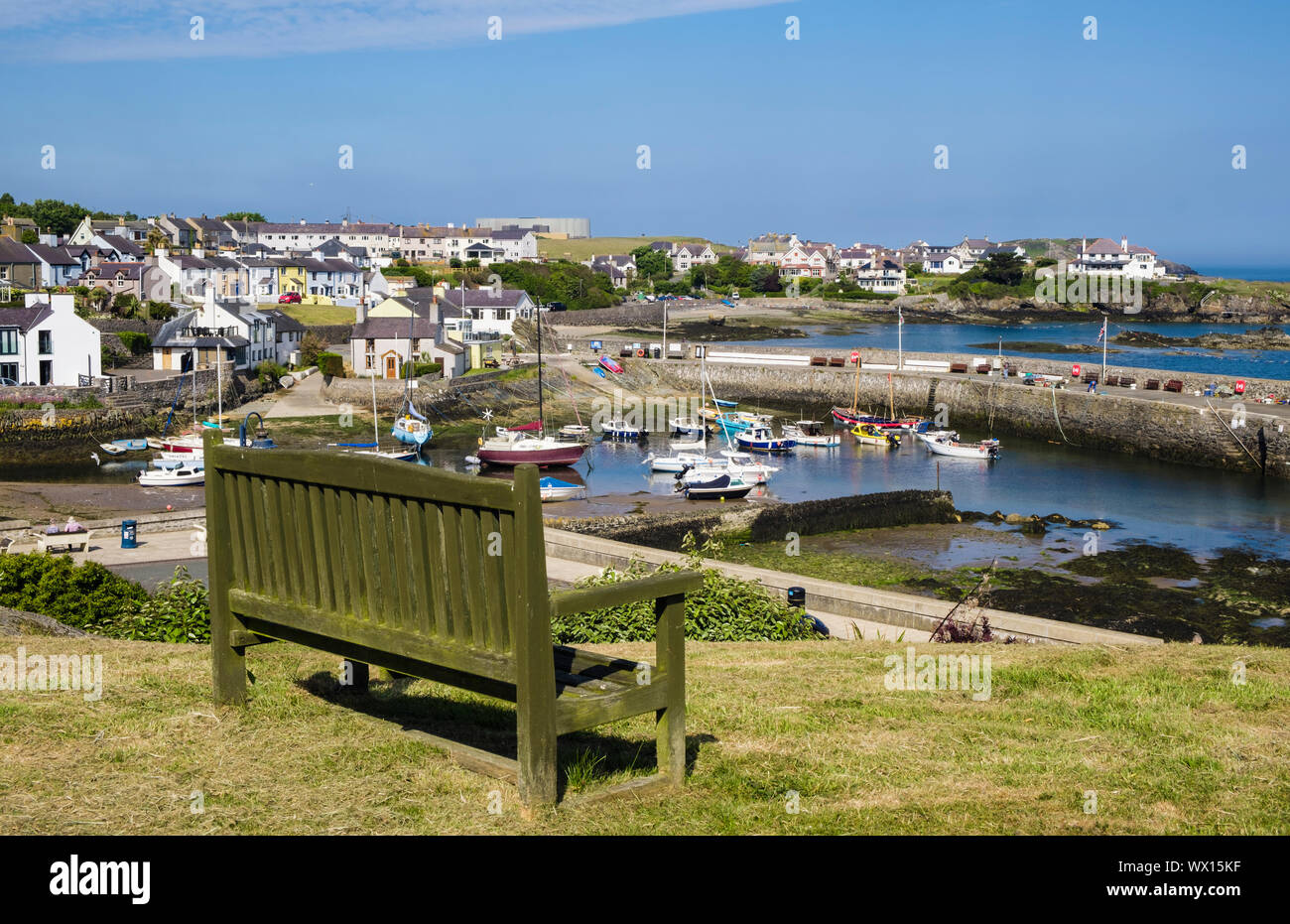 Svuotare il sedile unico che si affaccia sul porto di villaggio in Cemaes Bay. Cemaes, Isola di Anglesey, Galles, Regno Unito, Gran Bretagna Foto Stock