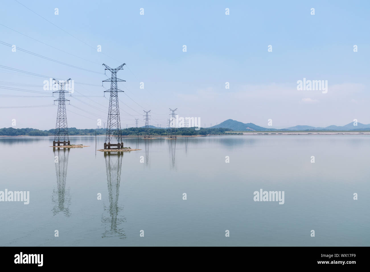 Potenza torre di trasmissione e riflessione sul lago Foto Stock