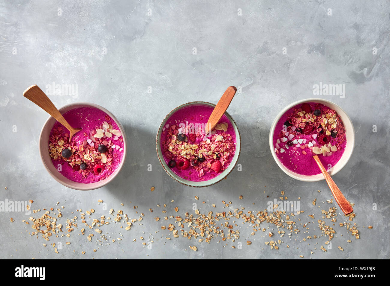 Delizioso preparato fresco barbabietole frullati con lamponi, granola e i semi di sesamo in una piastra con un cucchiaio su un livello di grigio concr Foto Stock