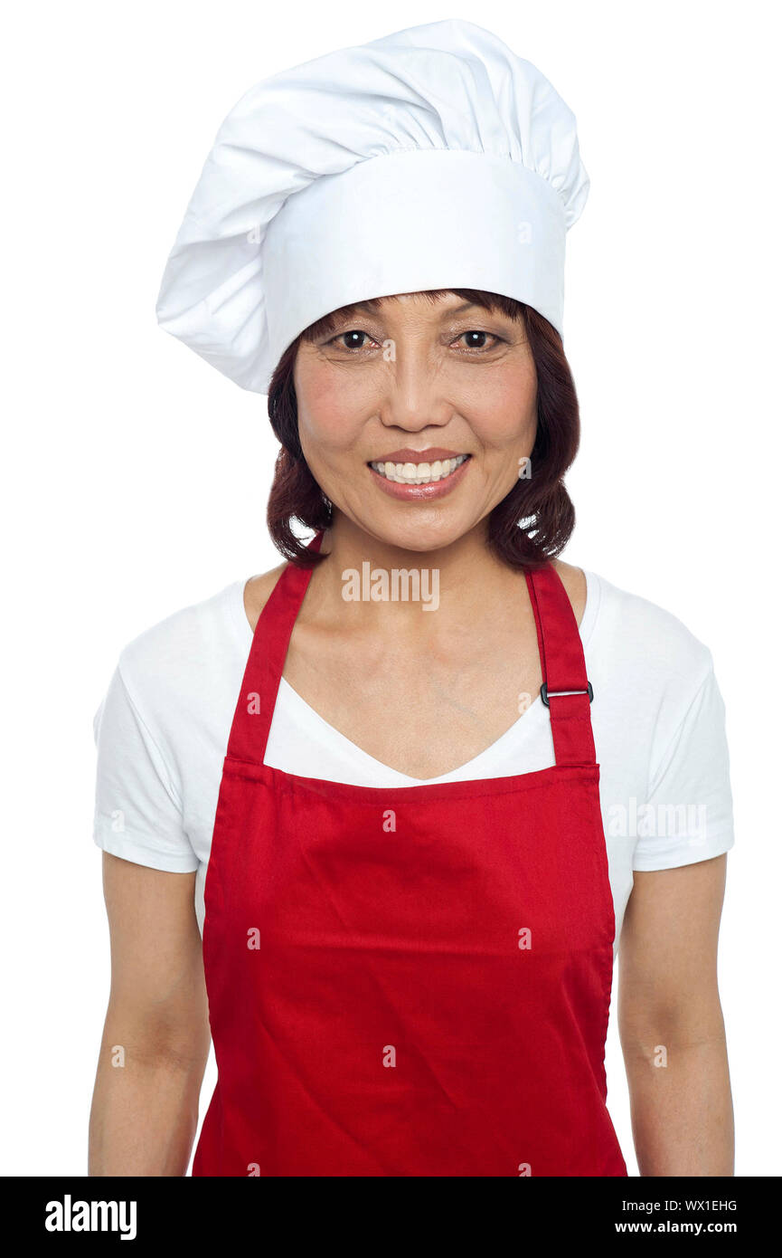Giovane donna sorridente chef indossando grembiule rosso e cappello da cuoco  di colore rosso Foto stock - Alamy