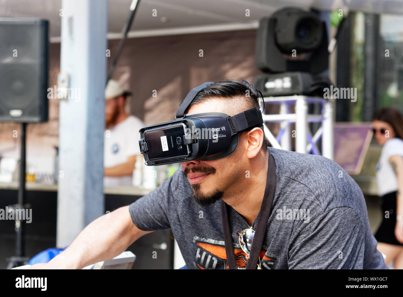 Un uomo che indossa la realtà virtuale gli occhiali e a cavallo di un simulatore di moto Foto Stock