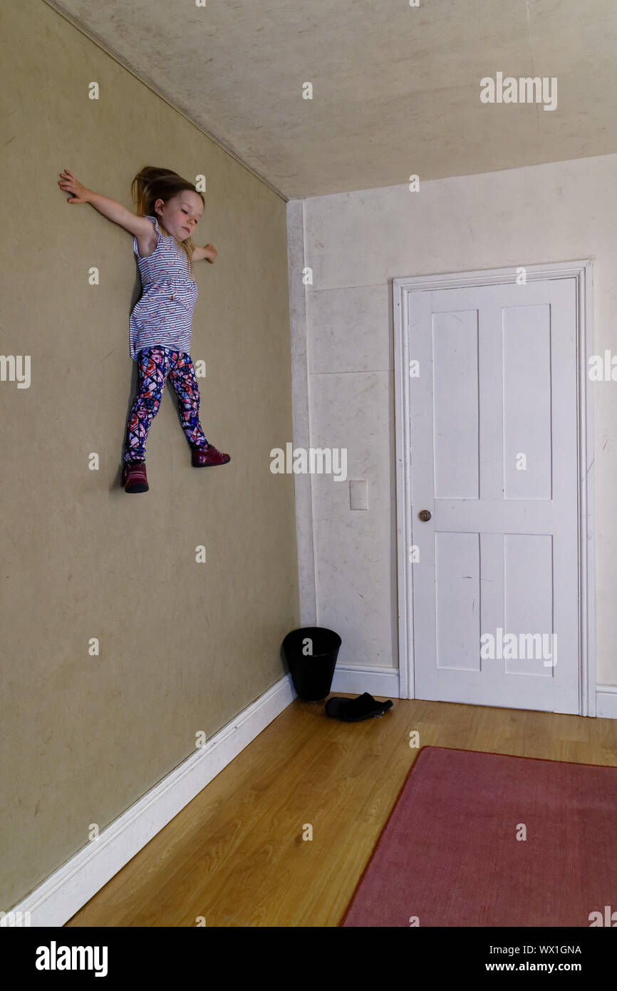 Una bambina in una camera progettata per illusioni sembra essere bloccato alla parete Foto Stock